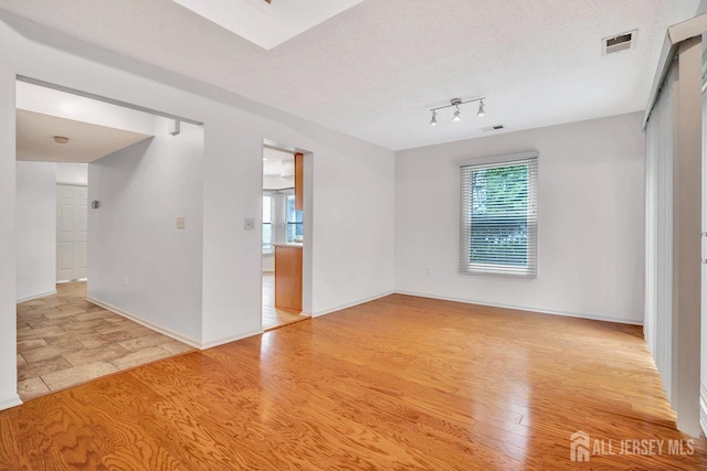 207 Manahan Rd, East Brunswick, NJ 08816 - spare room featuring healthy amount of natural light, light wood-style floors, and a textured ceiling