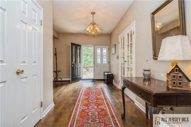 doorway to outside with a baseboard heating unit, dark wood-type flooring, and an inviting chandelier