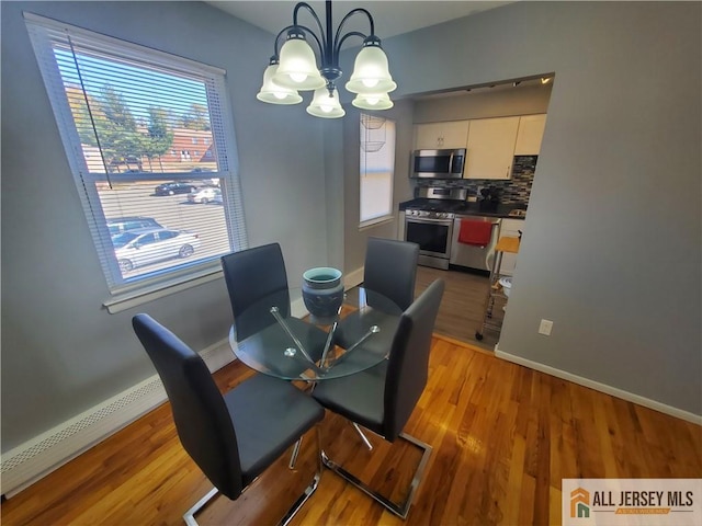 dining space with light wood-type flooring, a notable chandelier, and baseboard heating