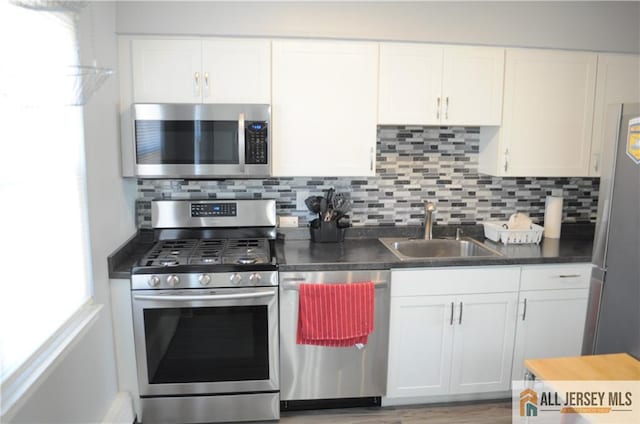 kitchen featuring white cabinetry, appliances with stainless steel finishes, sink, and backsplash