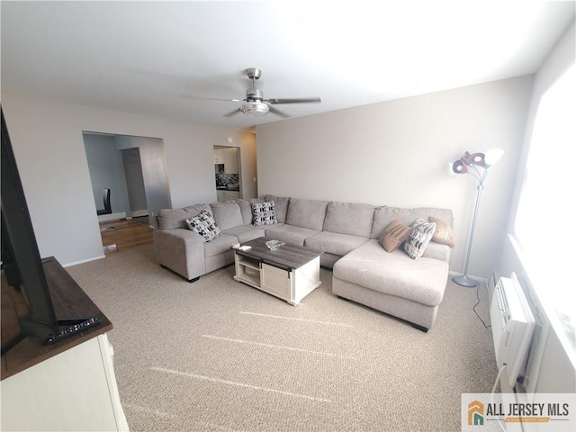 carpeted living room featuring a wall unit AC and ceiling fan