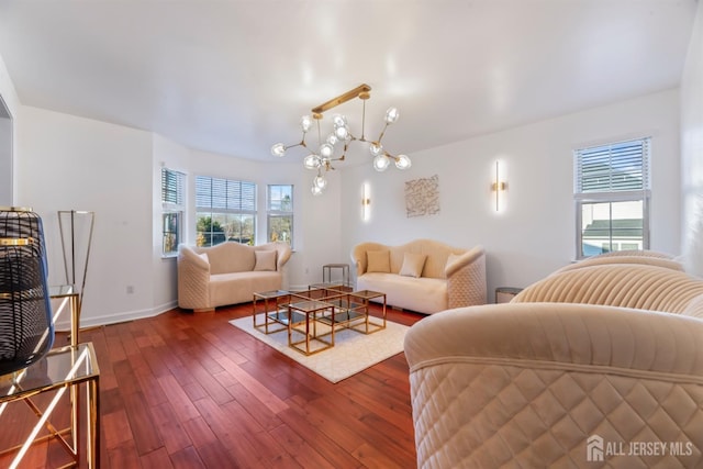 living room with dark wood-type flooring, plenty of natural light, and an inviting chandelier