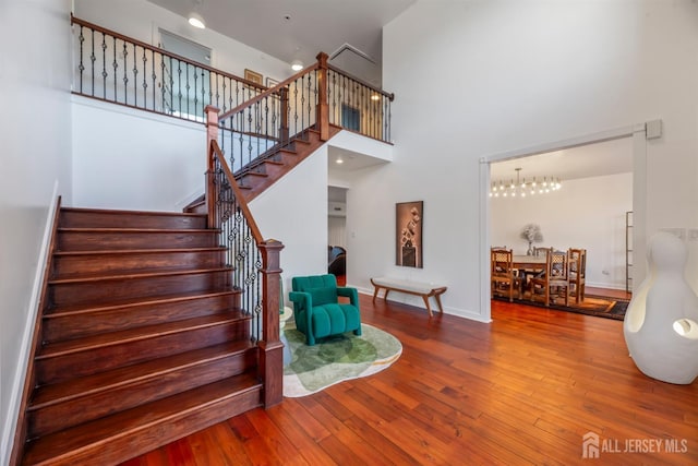 stairs with a towering ceiling and hardwood / wood-style floors