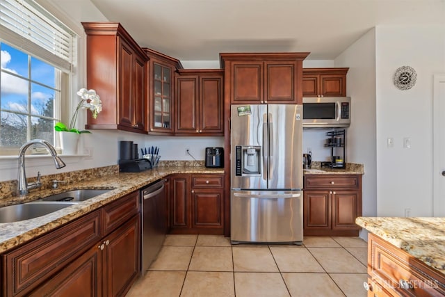 kitchen featuring light tile patterned floors, appliances with stainless steel finishes, light stone counters, and sink