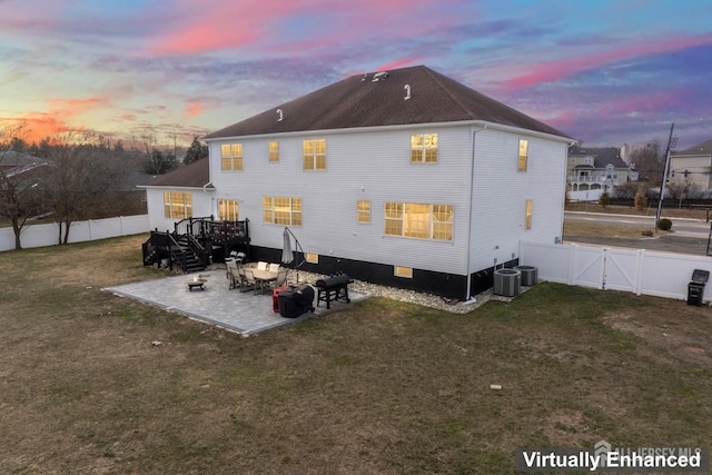 back house at dusk featuring a patio area and a yard