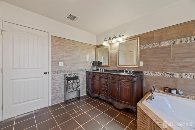 bathroom featuring a relaxing tiled tub, tile walls, vanity, and tile patterned flooring