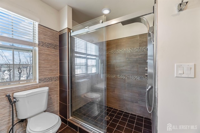 bathroom featuring toilet, tile patterned flooring, a healthy amount of sunlight, and an enclosed shower