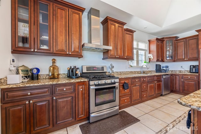 kitchen with wall chimney range hood, sink, stainless steel gas range, light tile patterned floors, and light stone counters