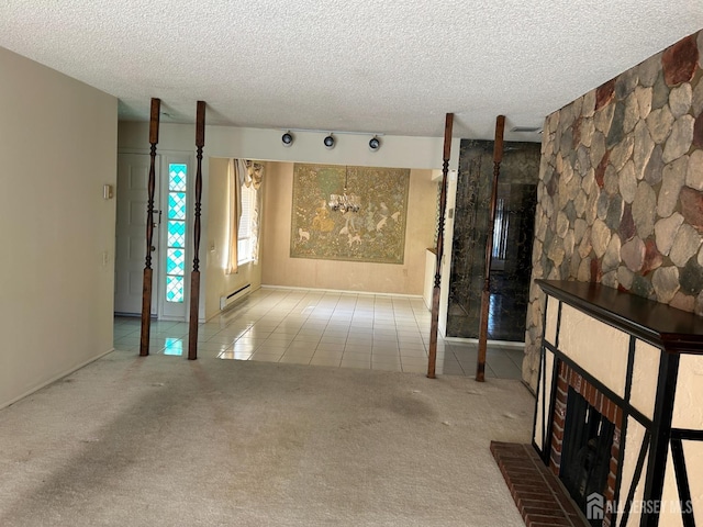 unfurnished living room featuring a brick fireplace, a baseboard heating unit, light carpet, and a textured ceiling