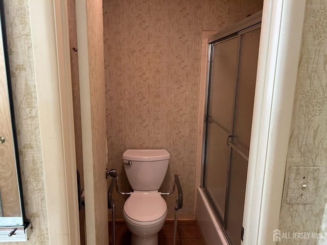 bathroom with tile patterned flooring, toilet, wallpapered walls, and shower / bath combination with glass door