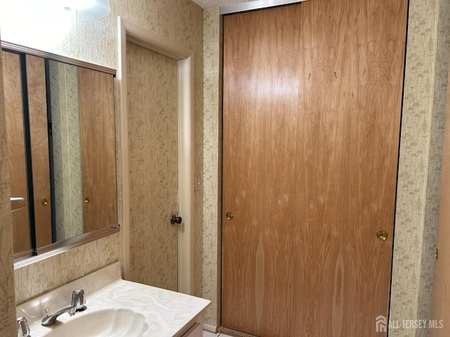 bathroom with wallpapered walls and vanity