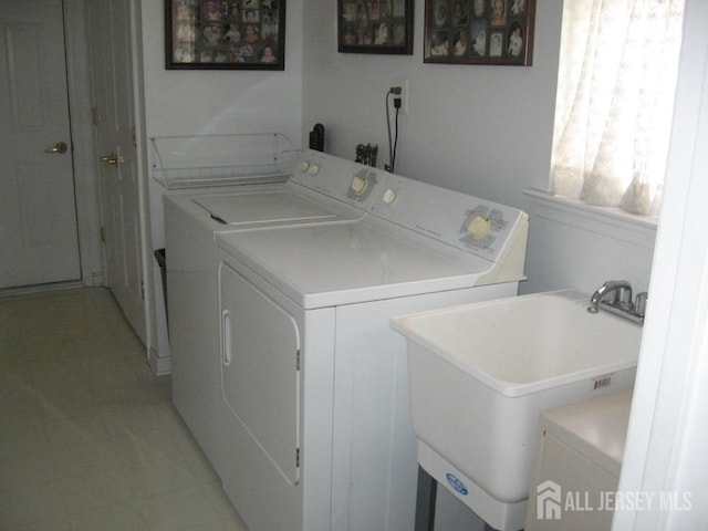 laundry area with a sink, laundry area, light tile patterned flooring, and washing machine and dryer