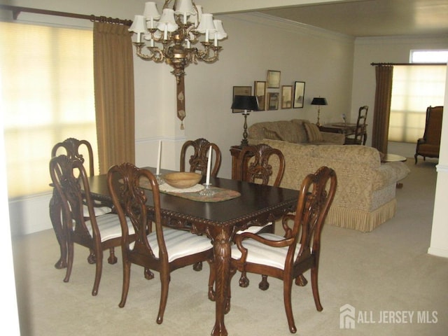 dining room featuring a notable chandelier, carpet, ornamental molding, and a wealth of natural light