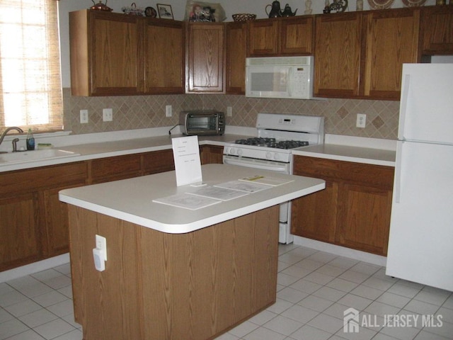 kitchen with brown cabinets, light countertops, decorative backsplash, a sink, and white appliances