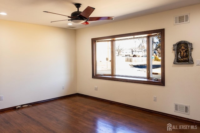 spare room with a ceiling fan, dark wood finished floors, visible vents, and baseboards