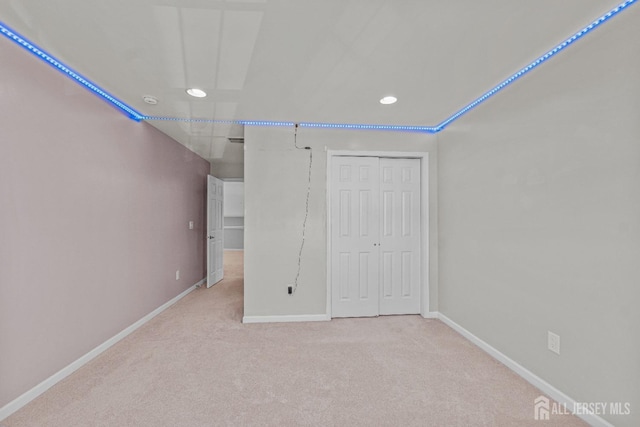 unfurnished bedroom with baseboards, a closet, recessed lighting, and light colored carpet