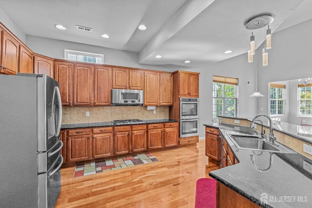 kitchen with visible vents, brown cabinets, a sink, stainless steel appliances, and backsplash