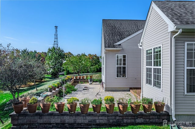 view of side of property featuring a patio area and roof with shingles