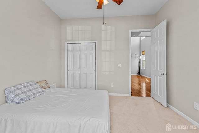 carpeted bedroom with a ceiling fan, baseboards, and a closet