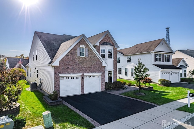 view of front of home with brick siding, central AC unit, a garage, driveway, and a front lawn