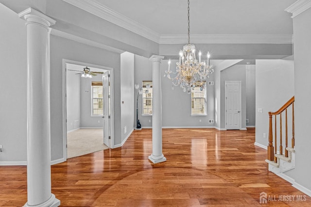 unfurnished dining area with crown molding, decorative columns, stairway, wood finished floors, and ceiling fan with notable chandelier