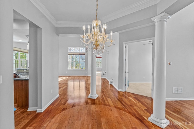 unfurnished dining area featuring plenty of natural light, decorative columns, visible vents, and wood finished floors