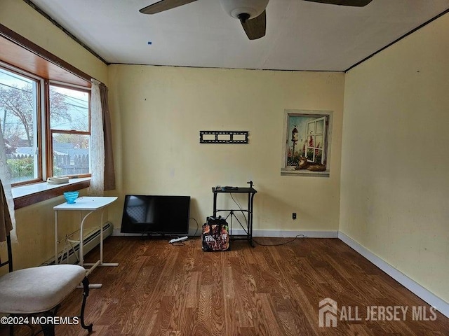 interior space featuring dark hardwood / wood-style flooring, ceiling fan, and a baseboard heating unit