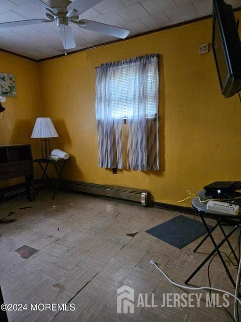 spare room featuring ceiling fan and a baseboard heating unit