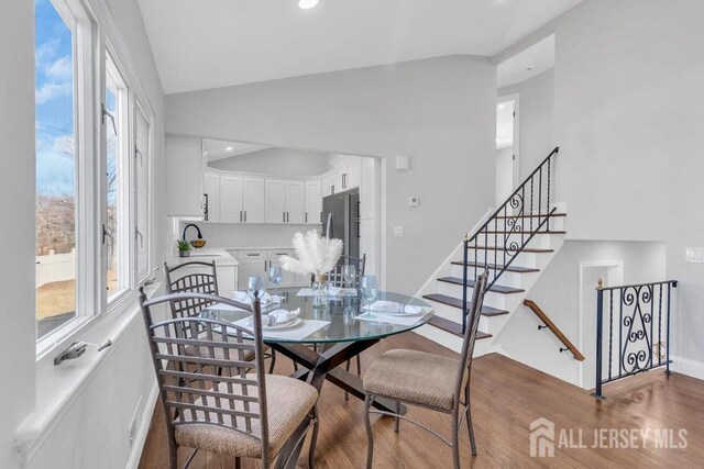 dining space featuring vaulted ceiling, wood-type flooring, and sink