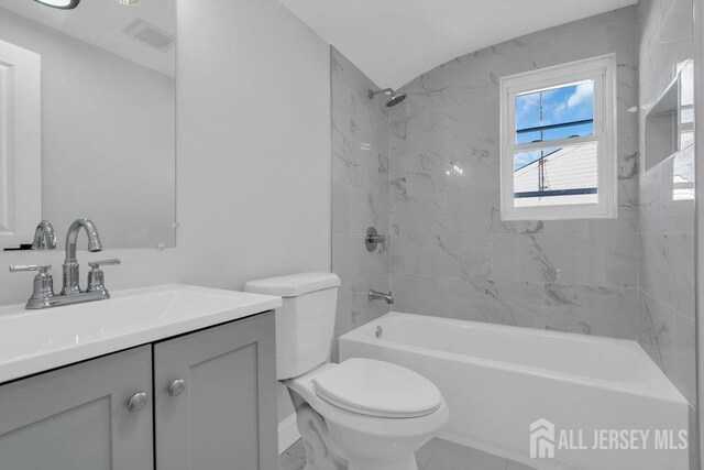 full bathroom featuring toilet, tiled shower / bath combo, and vanity