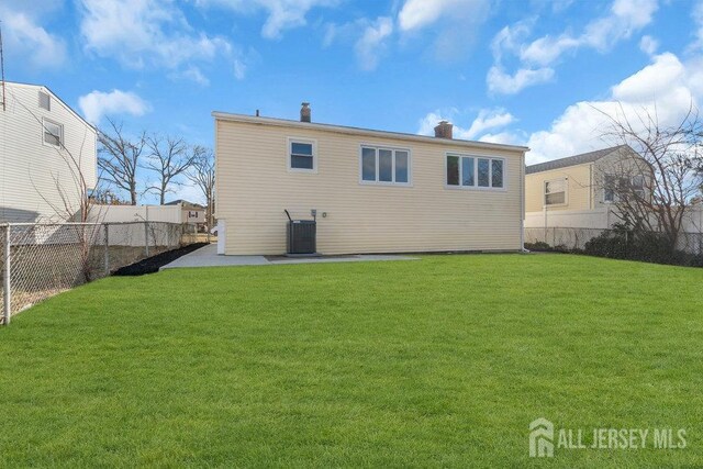 rear view of property with central AC and a lawn