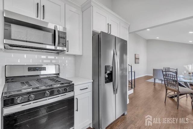 kitchen with hardwood / wood-style floors, decorative backsplash, stainless steel appliances, and white cabinetry