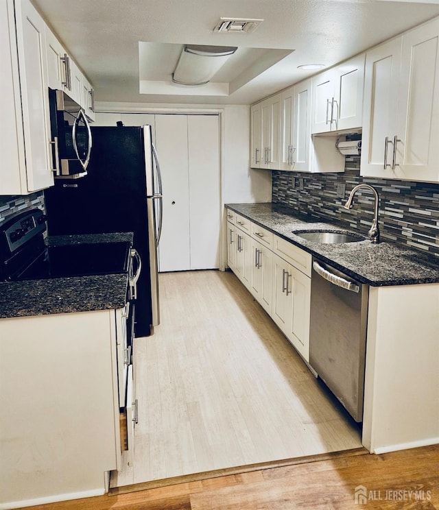 kitchen with a sink, stainless steel appliances, visible vents, backsplash, and white cabinets