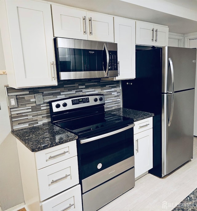 kitchen featuring stainless steel appliances, white cabinetry, light wood finished floors, and decorative backsplash
