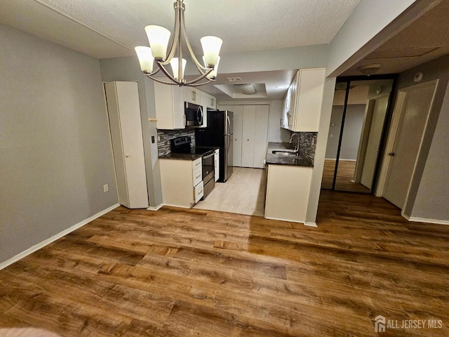 kitchen with a sink, a chandelier, dark countertops, tasteful backsplash, and appliances with stainless steel finishes