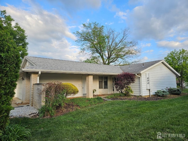 single story home featuring brick siding, roof with shingles, and a front yard