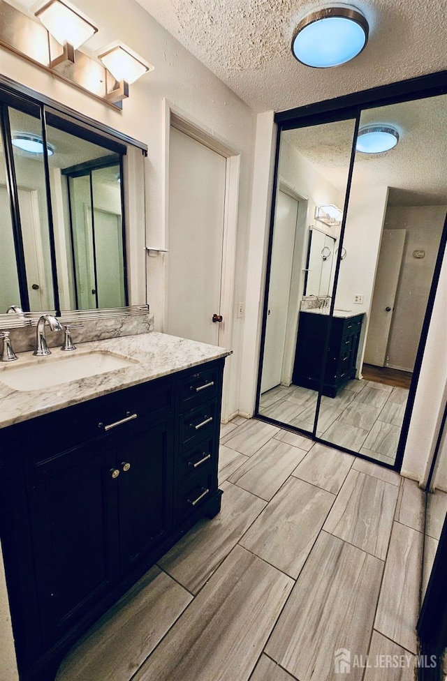 bathroom with a textured ceiling, vanity, and wood finish floors