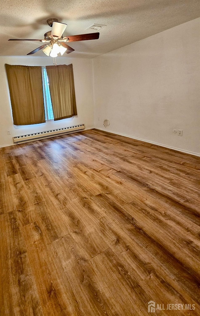 empty room featuring a ceiling fan, a textured ceiling, wood finished floors, and a baseboard radiator