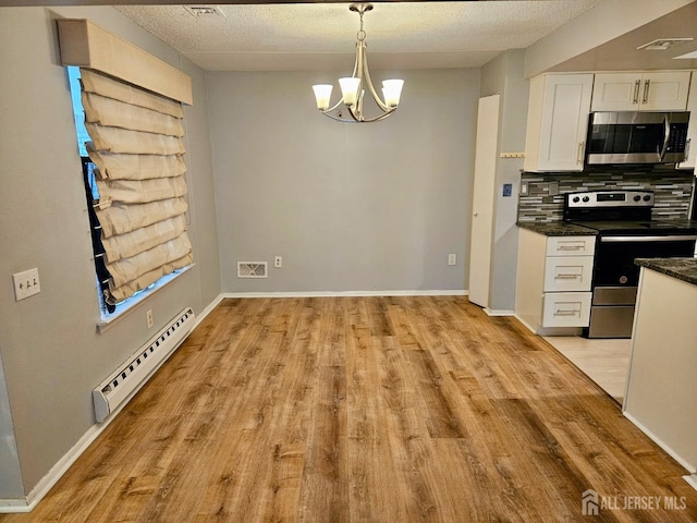 kitchen with baseboard heating, light wood finished floors, a chandelier, white cabinets, and appliances with stainless steel finishes