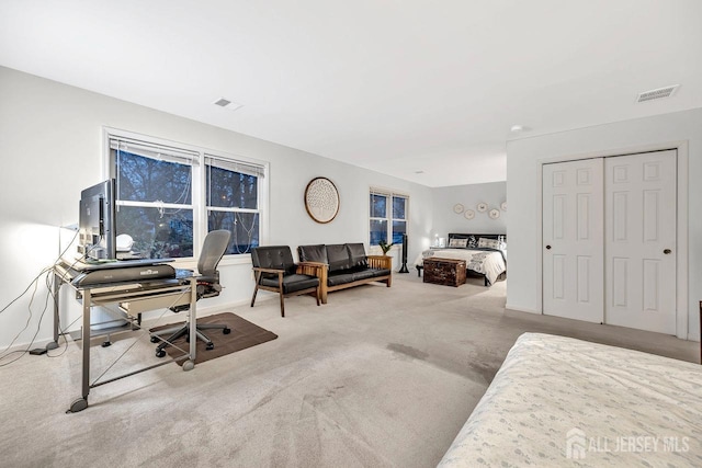 bedroom with a closet, visible vents, and carpet flooring