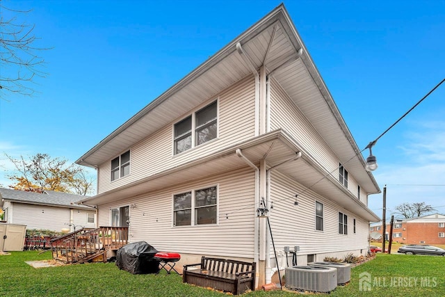 back of property featuring a wooden deck, central AC unit, and a yard