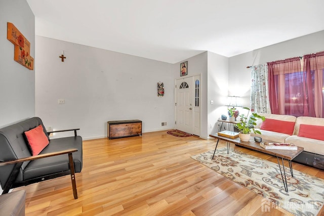 living area with light wood-type flooring, visible vents, and baseboards