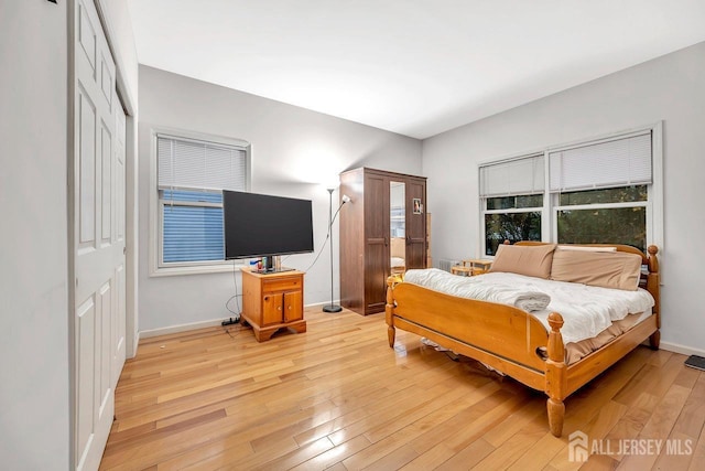 bedroom with a closet, baseboards, and light wood finished floors