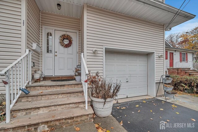 doorway to property with a garage and aphalt driveway