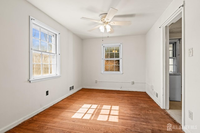 spare room with visible vents, baseboards, a ceiling fan, and wood finished floors