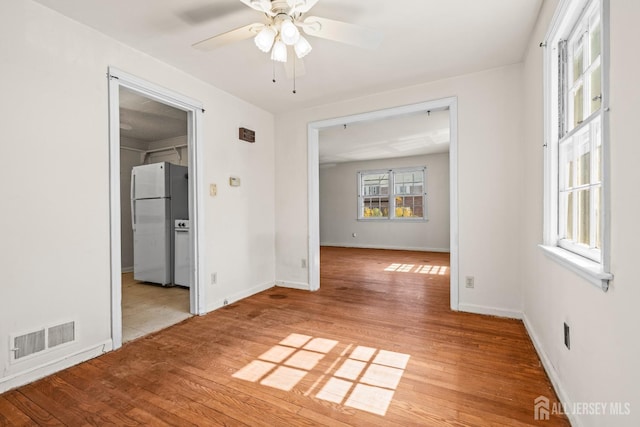 unfurnished room featuring light wood-type flooring, visible vents, baseboards, and ceiling fan