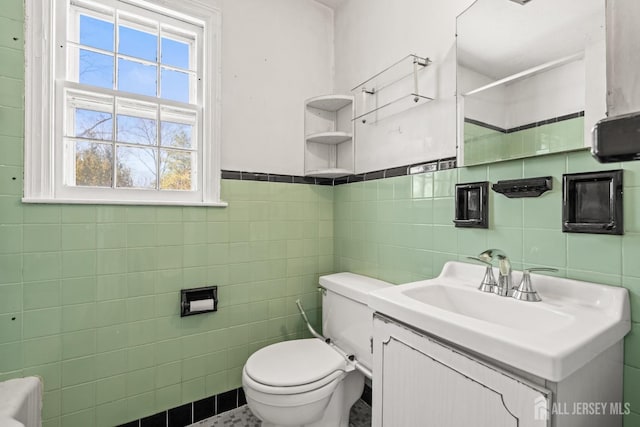 bathroom with toilet, tile walls, and vanity