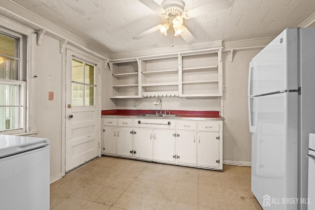 kitchen with a sink, light floors, freestanding refrigerator, white cabinetry, and open shelves