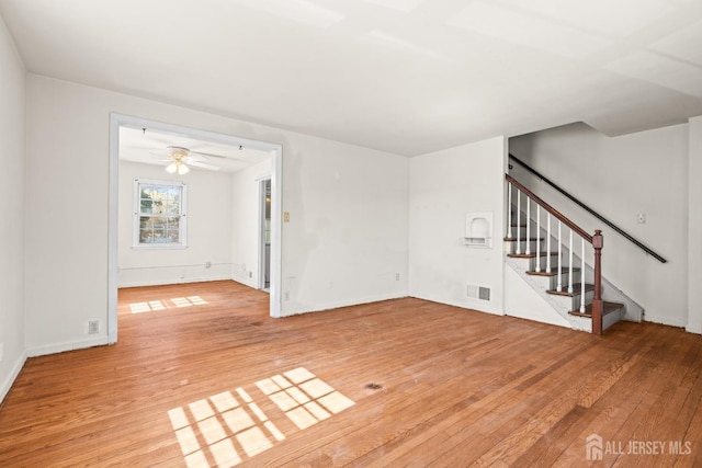 unfurnished living room with light wood-type flooring, visible vents, and stairs