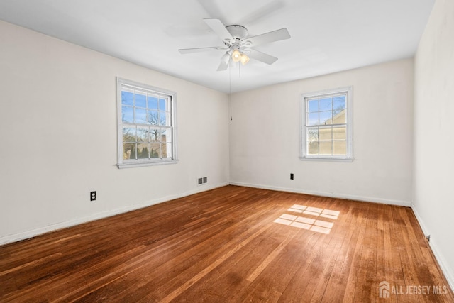 empty room featuring visible vents, baseboards, a ceiling fan, and wood-type flooring